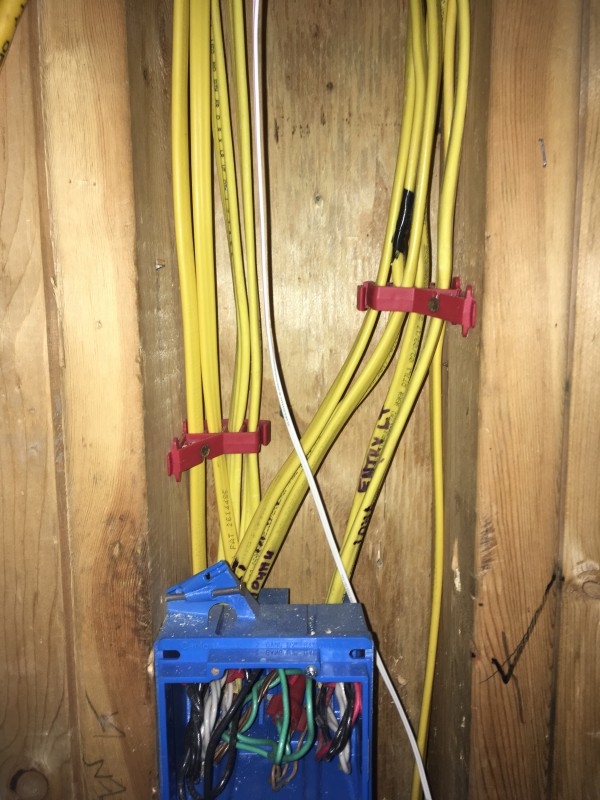 We weren't allowed to staple more than two wires to a 2x4, so we had to split large groups of wires and use the red holders (shown) to stack them.