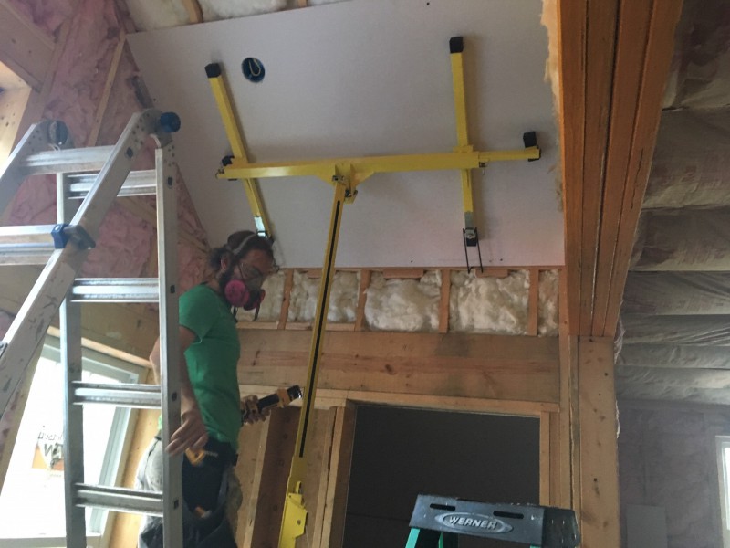 Using the drywall lift to hang ceiling pieces at an angle on our cathedral ceiling. We couldn't set the list on the stairs, so we had to remove the base and balance it on a single step.