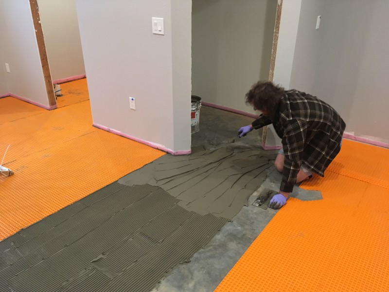 John using a notched trowel to spread the mortar where we'll be placing another piece of the orange uncoupling membrane